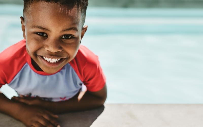 a boy in a pool smiling at the camera